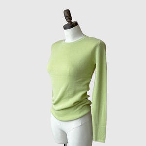 May include: A light green long-sleeved sweater on a white mannequin.