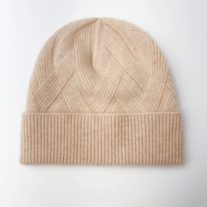 May include: A beige knitted beanie with a diamond pattern on the crown and a ribbed brim.