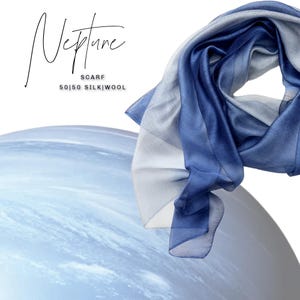 May include: A blue and white scarf with the word "Neptune" in script. The scarf is made of 50% silk and 50% wool. The scarf is draped over a light blue, spherical shape. The scarf is a stylish accessory.