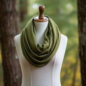 May include: A green infinity scarf made of soft fabric, displayed on a white mannequin.