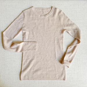May include: A light beige long-sleeved sweater with a crew neck.