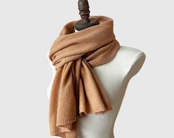 May include: A brown cashmere scarf draped over a white mannequin. The scarf is soft and luxurious, perfect for keeping warm in the winter.