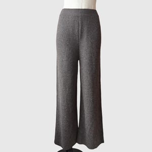 May include: Grey wide-leg trousers made from a soft, knitted fabric. The trousers have a relaxed fit and a slightly flared leg.