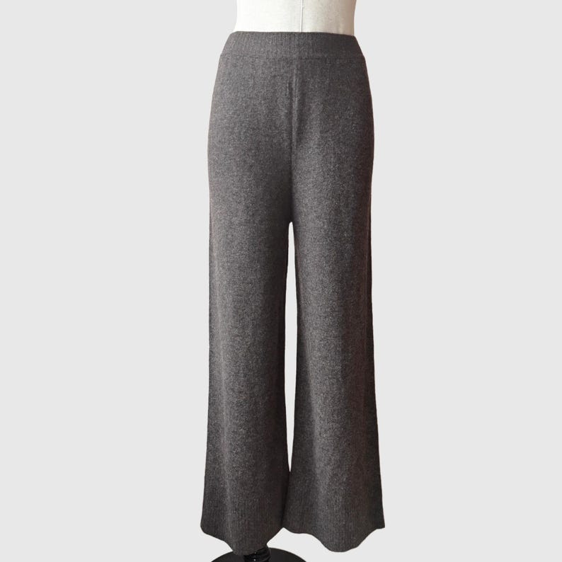 May include: Grey wide-leg trousers made from a soft, knitted fabric. The trousers have a relaxed fit and a slightly flared leg.