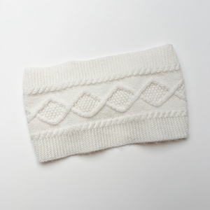 May include: A white knitted headband with a cable knit design. The headband features a textured pattern of diamonds and braided details, offering a cozy and stylish accessory. The headband is made of soft, warm material.