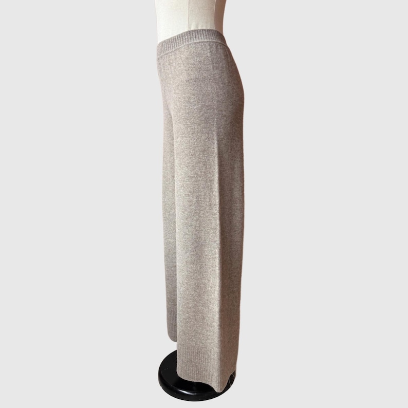 May include: A pair of wide-leg trousers in a light grey colour. The trousers are made of a soft, knitted fabric and have a relaxed fit.