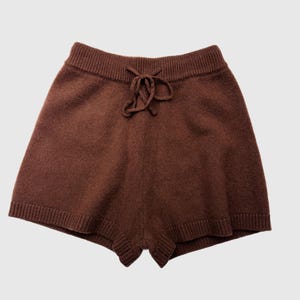 May include: Brown knit shorts with a drawstring waist. The shorts have a ribbed waistband and hem. The fabric appears soft and comfortable. The shorts are a solid brown color.