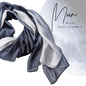 May include: A gradient blue and silver scarf made of 50/50 silk and wool. The scarf is draped over a white background with a moon image in the background. The text "Moon Scarf 50/50 Silk/Wool" is visible in the image.