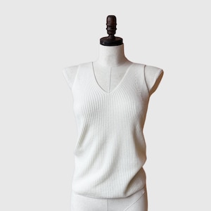 May include: A white ribbed sleeveless top with a v-neck.