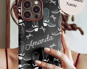 May include: Black phone case with a repeating pattern of white cowboy boots and bows. The name "Amanda" is written in a cursive font. The case has a red border and a camera cutout.