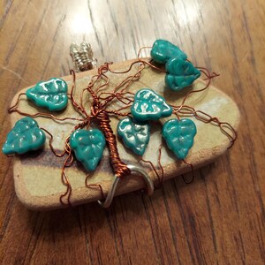 May include: A wire-wrapped tree with teal green glass leaves on a brown stone base.