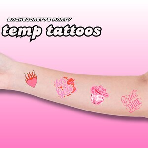 Può includere: Tatuaggi temporanei rosa a tema addio al nubilato. I disegni includono un cuore con fiamme, il testo "Let's Go Girls", una palla da discoteca con un cappello da cowboy e il testo "Bride Tribe". Sono visibili anche le parole "temp tattoos".