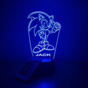 May include: Blue LED night light featuring a silhouette of Sonic the Hedgehog with the name "JACK" printed below. The light comes with a remote control.