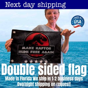 May include: A double-sided black flag featuring a red and black dinosaur graphic with the text "MAKE RAPTOR RUNS FREE AGAIN." The flag has grommets for hanging and the words "Double sided flag" are displayed.