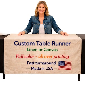 May include: A beige custom table runner with blue, green, red, and white text. The text reads "Custom Table Runner," "Linen or Canvas," "Full color - all over printing," "Fast turnaround," and "Made in USA." An American flag is also visible.