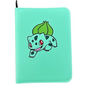 May include: A teal blue leatherette wallet featuring a cartoon image of a green Bulbasaur Pokemon.