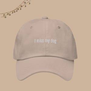 May include: A beige baseball cap with the text "I miss my dog" embroidered in white on the front.
