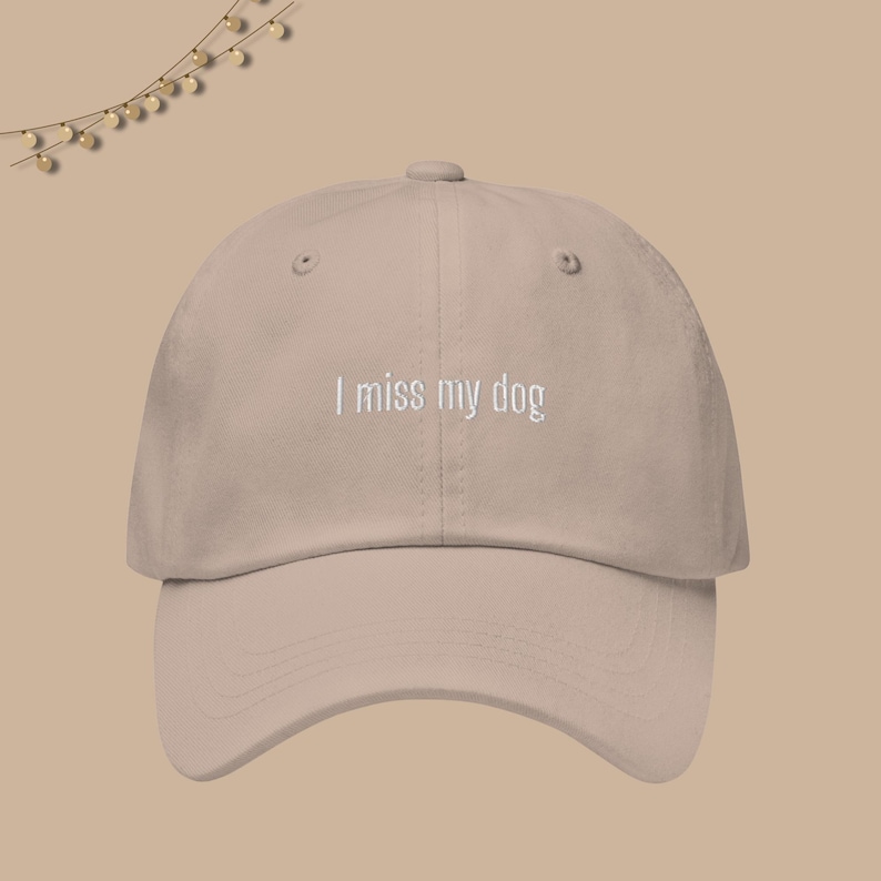 May include: A beige baseball cap with the text "I miss my dog" embroidered in white on the front.