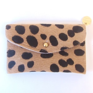 May include: A small, tan and black leopard print wallet with a gold button closure.