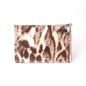 May include: A brown and white animal print wallet with a silver charm that says "La Casa".