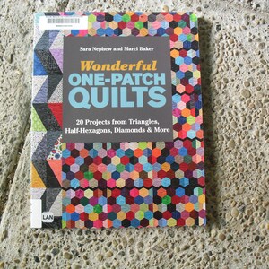 May include: Book cover with the title "Wonderful One-Patch Quilts" by Sara Nephew and Marci Baker. The cover features a colorful patchwork quilt design with a variety of geometric shapes, including triangles, half-hexagons, diamonds, and more. The book promises 20 projects.