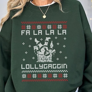 May include: Green Christmas sweater with a white graphic of a person falling down a chimney with the text "Fa La La La La" and "Lollygaggin".