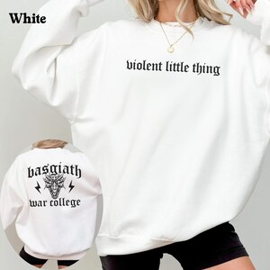 Pode incluir: Camisola branca com o texto "violent little thing" estampado na frente e "basgiath war college" com um gr&aacute;fico de drag&atilde;o estampado nas costas.