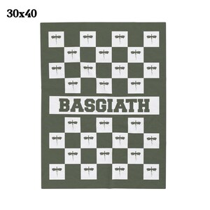 K&ouml;nnte beinhalten: Eine gr&uuml;n-wei&szlig;e karierte Wolldecke mit einem sich wiederholenden Muster aus stilisierten Libellen. Die Decke hat das Wort "BASQUIAT" in wei&szlig;en Buchstaben auf einem schwarzen Band in der Mitte aufgedruckt.
