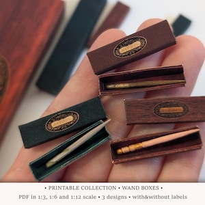 Peut inclure: Une collection de boîtes à baguettes miniatures aux finitions marron foncé, noir et imitation bois, chacune dotée d'une étiquette ovale. Les boîtes sont ouvertes pour révéler de petites baguettes fines aux tons or, bois clair et gris.