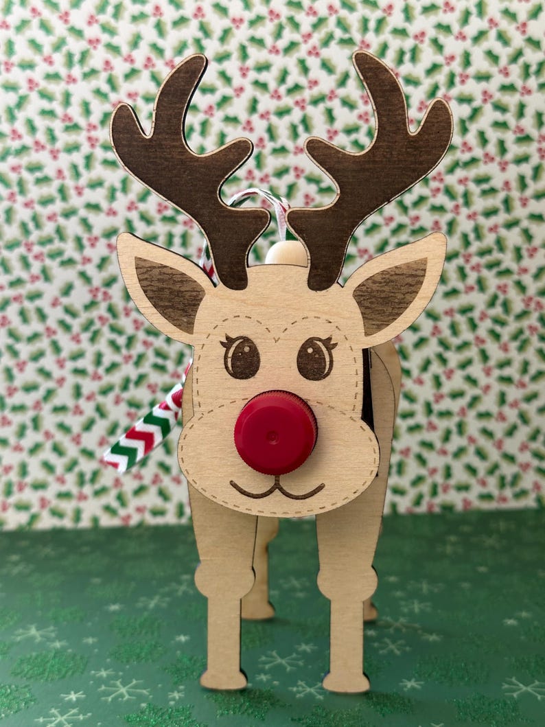 May include: Wooden reindeer ornament with a red bottle cap nose, brown antlers, and a red and white striped ribbon.