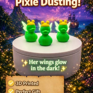 Puede incluir: Tres figuras de patos de hadas verdes con sombreros amarillos y alas brillantes se exhiben en una plataforma blanca. El texto "Perfect for Pixie Dusting!" está arriba. El texto "Her wings glow in the dark!" está debajo.