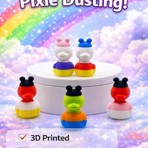 May include: Colorful duck-shaped figurines with various hat colors, including pink, blue, and black, are displayed on a white platform. The text "Perfect for Pixie Dusting!" is above the figurines. The image also includes the text "3D Printed", "Perfect Gift", and "Cruise / Park Ready".