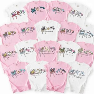 May include: A selection of pink and white t-shirts, each adorned with cartoon character illustrations. The designs include character ears, bows, and text, creating a whimsical aesthetic. The shirts are arranged in a circular pattern, showcasing the variety.