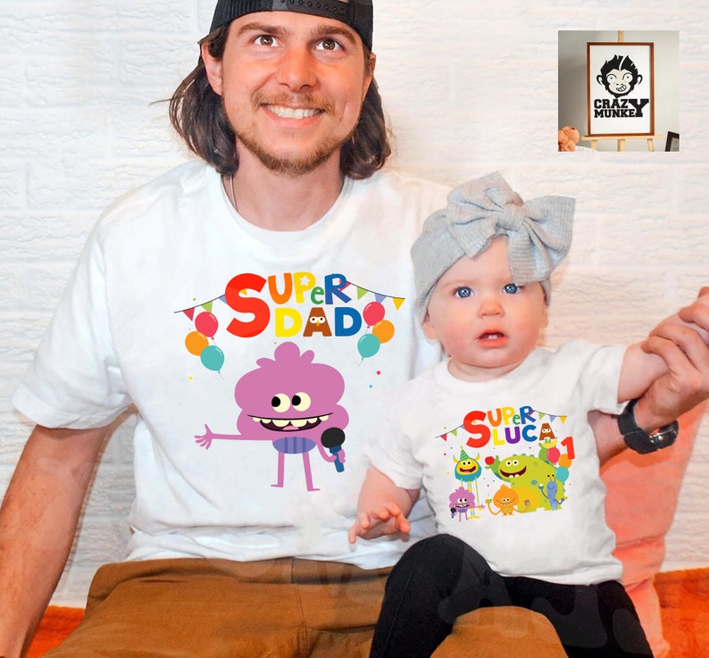 May include: White t-shirts with a colorful graphic of a cartoon character. The adult shirt says "Super Dad" and the child shirt says "Super Luca 1".