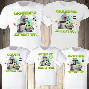 May include: White t-shirts with a graphic of a Mandalorian character holding a Grogu. The shirts have text that says "Grandpa", "Grandma", "Cousin", "Brother", and "Birthday Boy". One shirt says "Sebastian" and has the number "2".