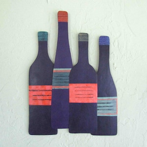 May include: Five purple wine bottles with red and blue stripes on a white textured background.