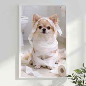 May include: A framed print featuring a light brown Chihuahua wrapped in white toilet paper. The dog is sitting in a bathroom setting with a toilet in the background. The dog is looking directly at the camera.