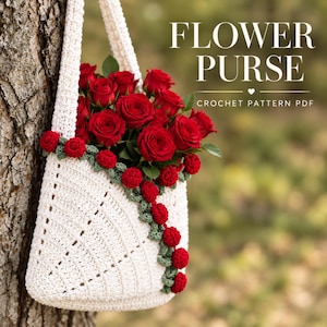 Puede incluir: Un bolso de ganchillo blanco con una enredadera diagonal de pequeñas flores rojas tejidas y hojas verdes, lleno de rosas rojas frescas. El texto FLOWER PURSE CROCHET PATTERN PDF es visible en la esquina superior derecha de la imagen.