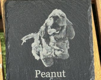 Könnte beinhalten: Ein schwarzer Schieferuntersetzer mit einem weißen, gravierten Bild eines Hundes mit herausgestreckter Zunge. Der Name des Hundes, "Peanut", ist unter dem Bild graviert.