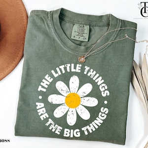 May include: A green t-shirt with a white daisy and the text "The little things are the big things".