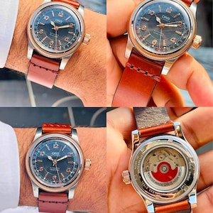 Puede incluir: Un reloj automático Oris con esfera oscura texturizada, bisel en tono oro rosa y números arábigos. El reloj cuenta con una correa de cuero marrón con costuras visibles y una parte posterior transparente que muestra el mecanismo de rotor rojo.
