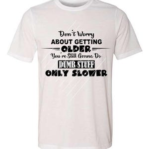May include: White t-shirt with black text that reads "Don't Worry About Getting Older, You're Still Gonna Do Dumb Stuff, Only Slower." The shirt has a crew neck and short sleeves.