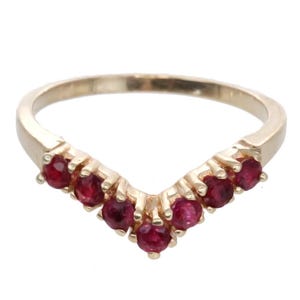 May include: A gold ring with a V-shaped band set with seven red gemstones.