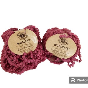 May include: Two balls of pink yarn labeled "Woolette" yarn. Each ball is 3.5 ounces and 48 yards. The yarn is 40% acrylic, 30% polyester, 15% wool, and 15% nylon.