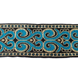 May include: Decorative trim with a black background, featuring a repeating pattern of teal and gold scrollwork. The trim has a woven texture and is suitable for various craft and sewing projects.