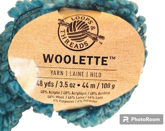 May include: A skein of bright blue textured yarn with a tan paper label. The label reads LOOPS & THREADS WOOLETTE, 48 yds / 3.5 oz, and lists a fiber content of 48% acrylic, 46% wool, and 6% polyester in a looped, fuzzy construction.