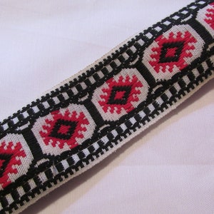 May include: Black and red woven trim with a geometric pattern. The trim has a white background with black and red squares.