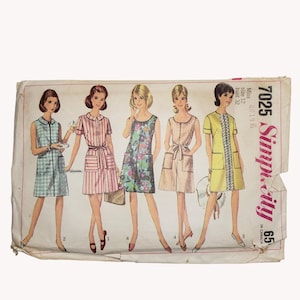 May include: Vintage Simplicity sewing pattern featuring five dress designs. The dresses are depicted in various styles, including striped, floral, and solid colors. The pattern includes the text "7025 Simplicity 65" and is marked "in Canada".