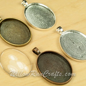 May include: Four oval-shaped pendant trays, two with a silver finish, one with a bronze finish, and one with a copper finish. The trays are on a wooden surface.  The trays are for crafting and can be used to create custom jewelry.