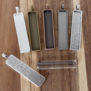 May include: Six silver, bronze, and copper rectangular pendant trays with a clear glass pendant tray.